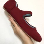 hand holding burgundy shoe in white background