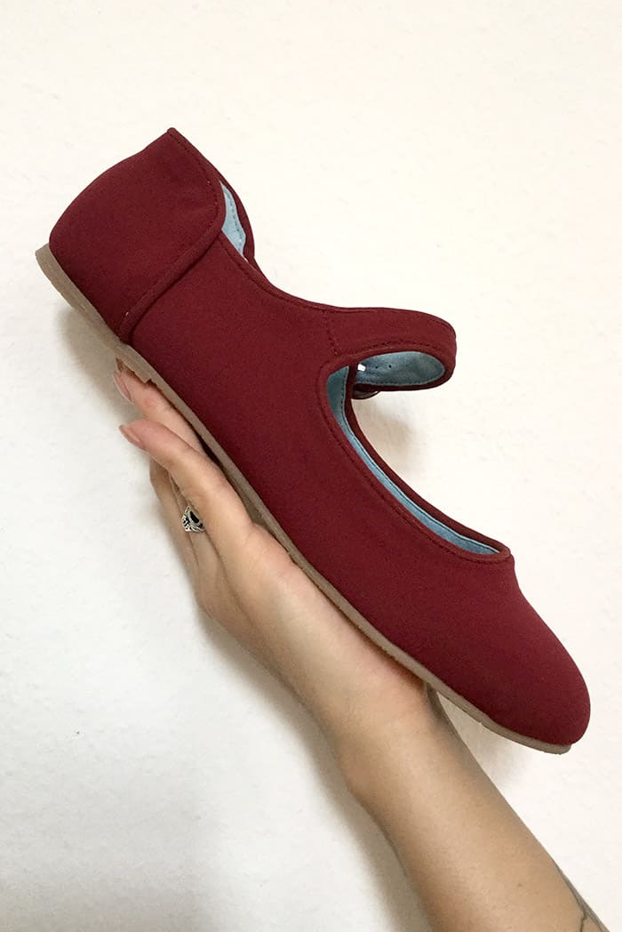 hand holding burgundy shoe in white background