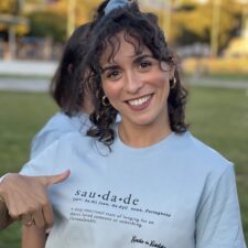 Camila pointing at the Saudade sentence on her blue t-shirt.